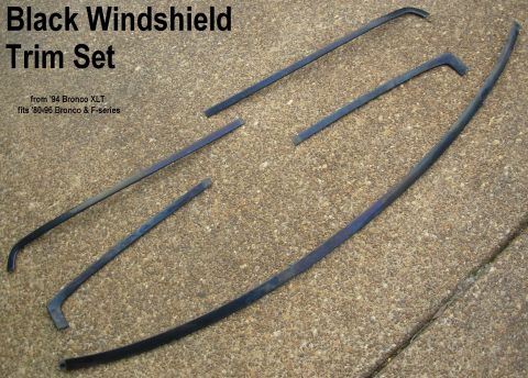 Black windshield trim molding set from 94 Bronco XLT laid on gravel