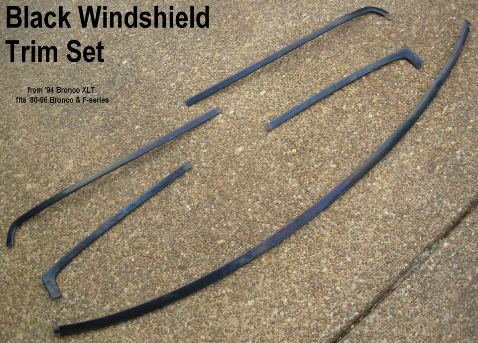 Black windshield trim molding set from 94 Bronco XLT laid on gravel