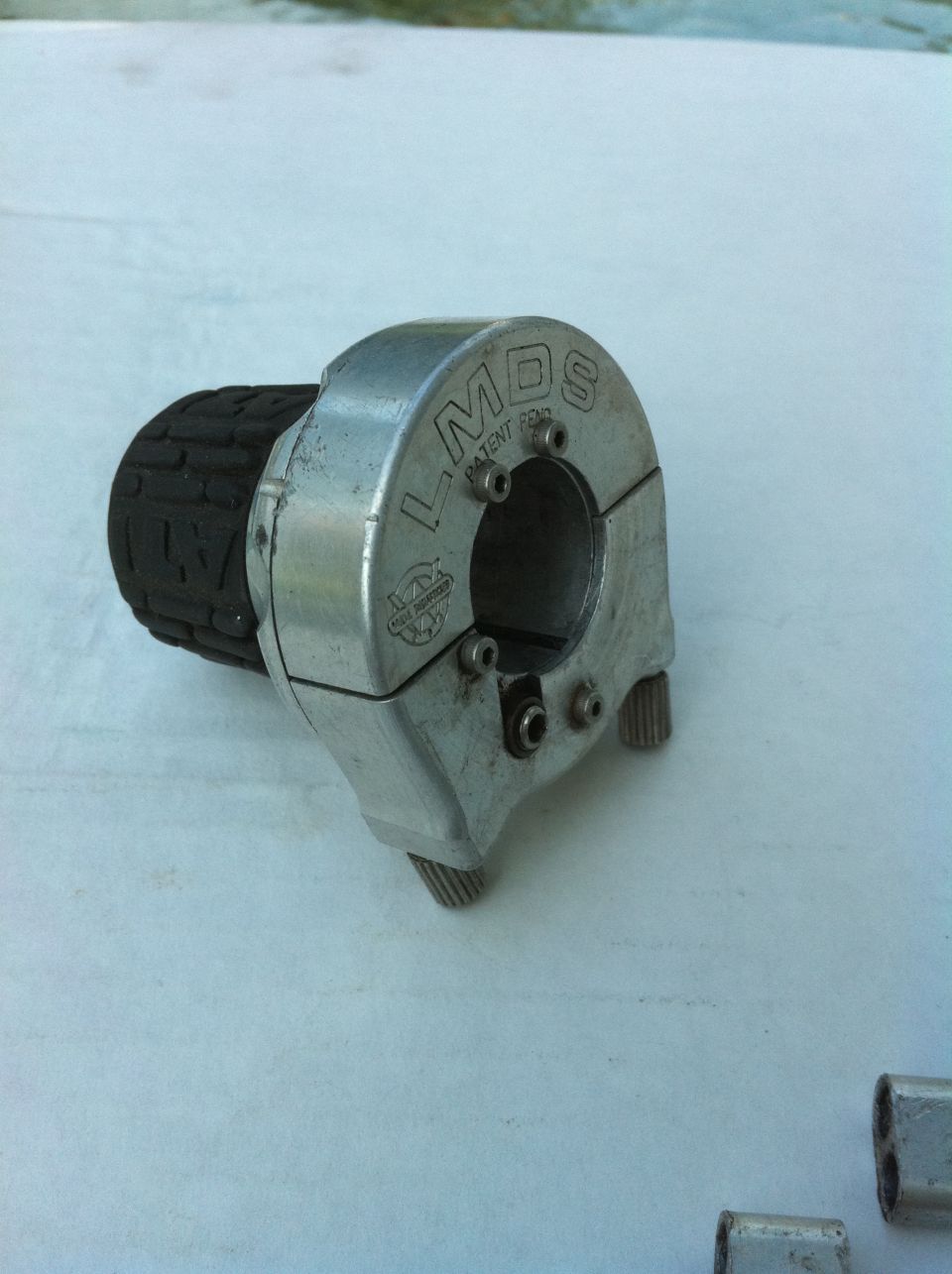 Silver LMDS handlebar clamp control with black twist grip on white surface