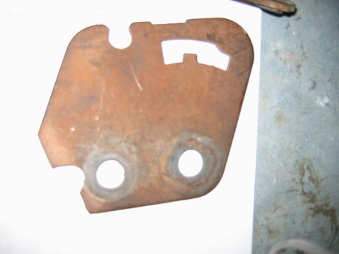 1992 Ford Bronco - A close-up view of a single, heavily rusted metal bracket with two circular holes and a shaped cutout.