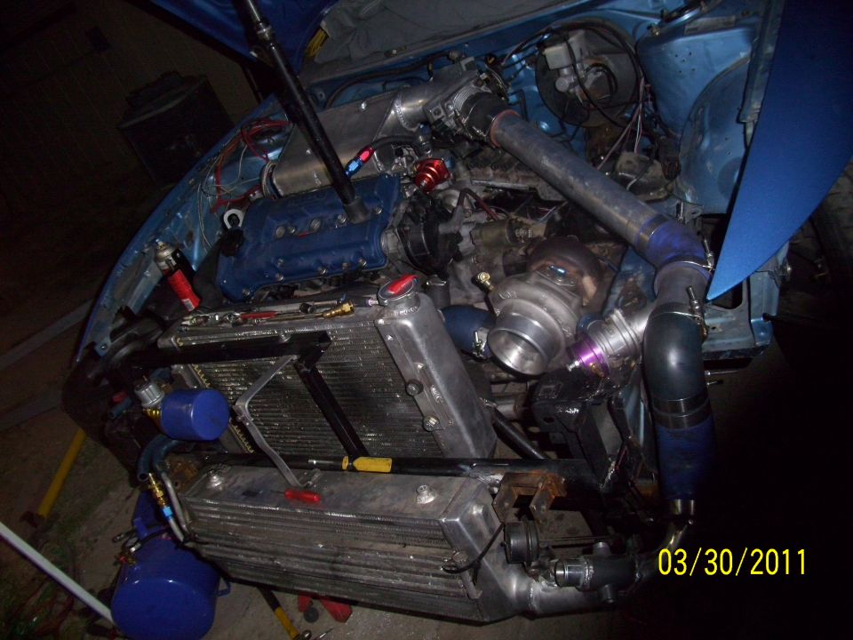 Car engine bay with turbocharger, intercooler, and custom piping. Hood is open