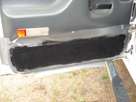 1992 Ford C-350 (Centurion Conversions) - A section of a vehicle's interior door panel shows black carpet padding attached with tape.