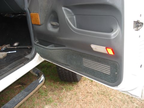 1992 Ford C-350 (Centurion Conversions) - Open rear door of a white truck showing a gray molded door panel with recessed pull cup, small storage tray, speaker grille in the carpeted…