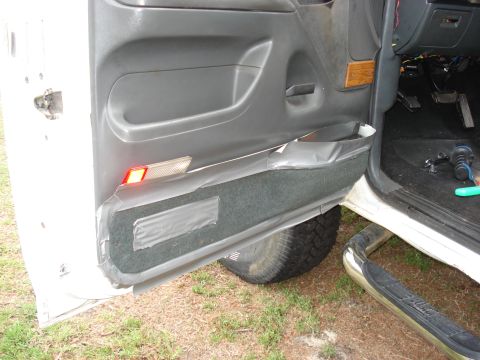 1992 Ford C-350 (Centurion Conversions) - Open driver's door on a white truck showing a gray door panel whose lower carpeted section is patched and held on with wide silver duct tap…