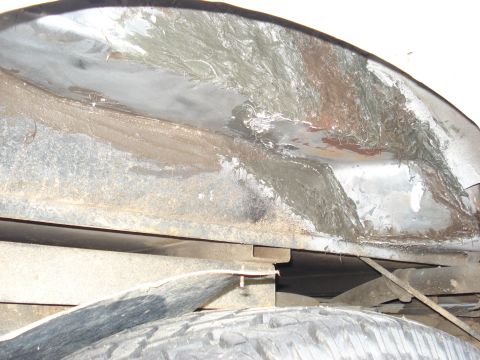 1992 Ford C-350 (Centurion Conversions) - Looking up inside a truck's rear wheel well at bare, scraped sheet metal where old undercoating has been stripped off, showing surface rust…
