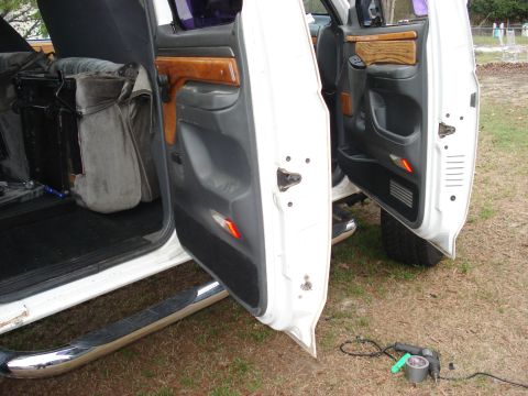 1992 Ford C-350 (Centurion Conversions) - Both driver-side doors of a white crew-cab truck stand open on a grassy lot, showing gray door panels with woodgrain trim inserts, amber re…