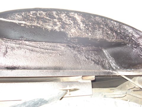 1992 Ford C-350 (Centurion Conversions) - Close-up under a truck body showing the inner wheel well and rocker area heavily coated in thick black undercoating spray, with runs and ro…