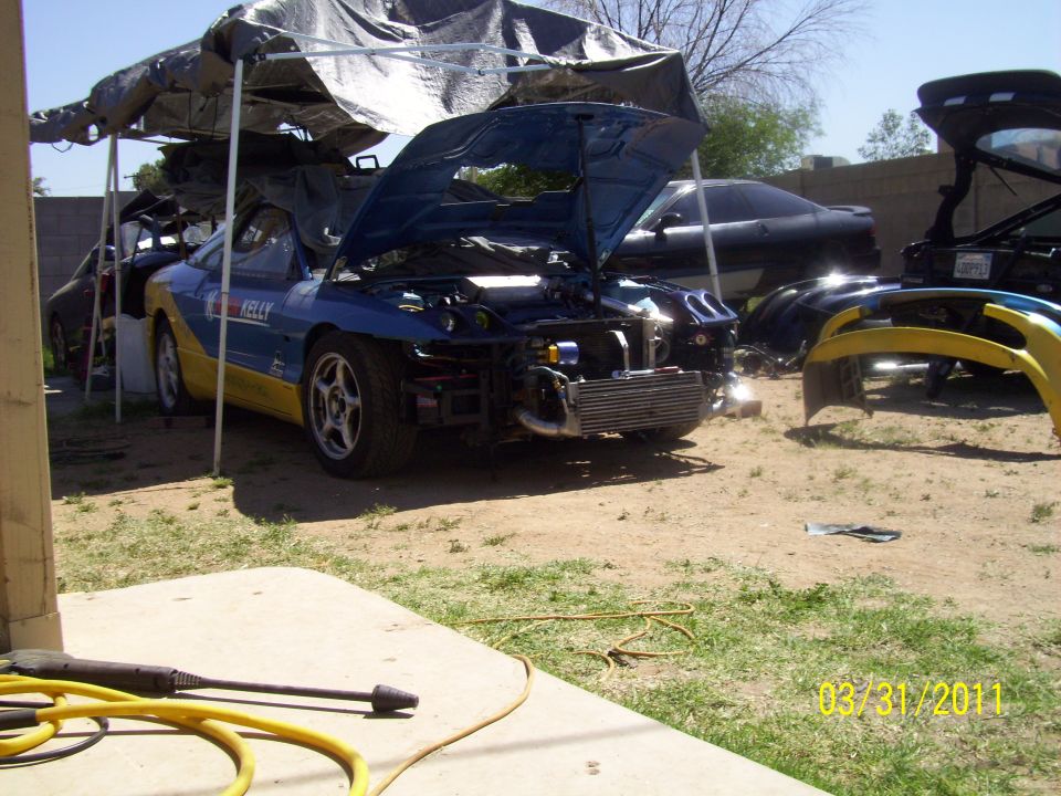 Blue and yellow car with hood open, front bumper removed, intercooler visible