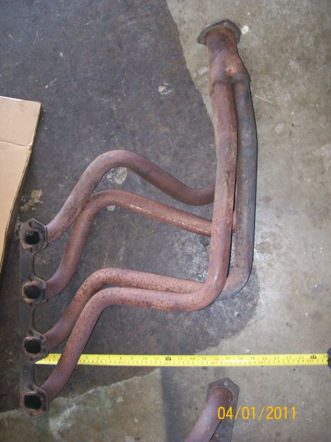 1970 Ford Bronco - Exhaust manifold shown with a yellow measuring tape on a concrete floor.