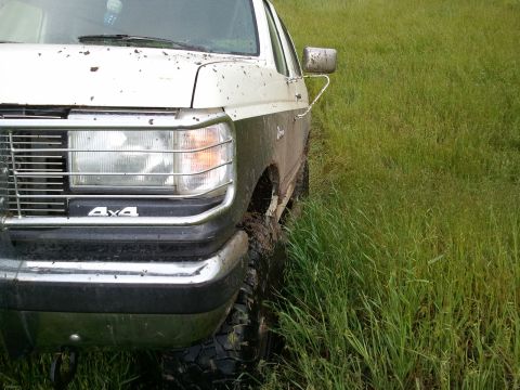 1989 Ford Bronco - Muddy 1989 Ford Bronco 4x4 parked in a grassy field.