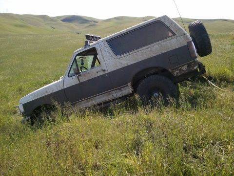 1989 Ford Bronco - This 1987 Ford Bronco appears to be stuck in a grassy field with its tires sunk into the terrain.