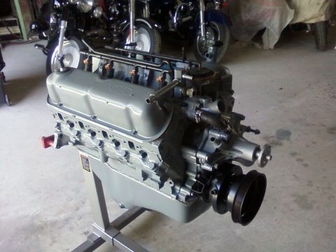 1990 Ford Bronco - Ford V8 engine on a stand, with motorcycles visible behind it.