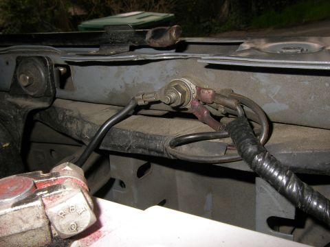 1990 Ford Bronco - Close-up of a chassis ground point on an engine bay inner fender, where several ring terminals are stacked on a bolt and nut against bare m…
