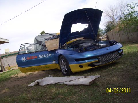 1995 Ford Probe - A blue and yellow 1995 Ford Probe is parked outdoors with its hood and door open, revealing its engine and interior.