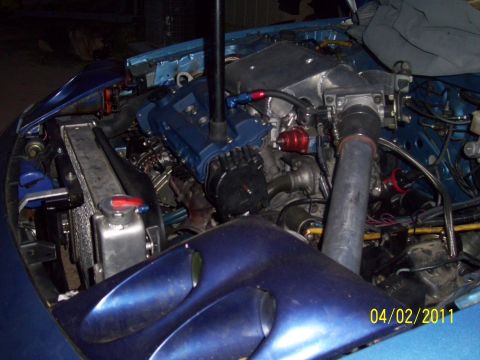 1995 Ford Probe - Customized engine bay a blue valve cover, large intake piping, and an aftermarket radiator, dated 04/02/2011.
