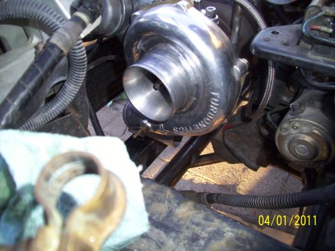 1995 Ford Probe - Close-up of a Turbonetics turbocharger being installed in an engine bay.