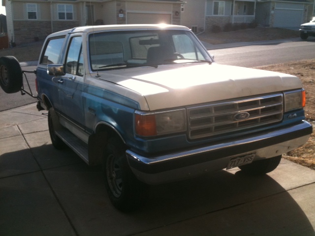 1988 Ford Bronco, blue and white, with rear-mounted spare tire