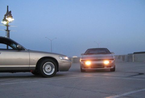 2000 Mercury Grand Marquis - Two cars are parked on a rooftop at dusk, one a sedan and the other a sports car.