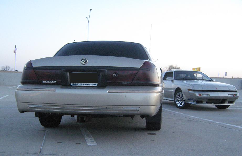 Rear of silver 2000 Mercury Grand Marquis with another silver car behind it
