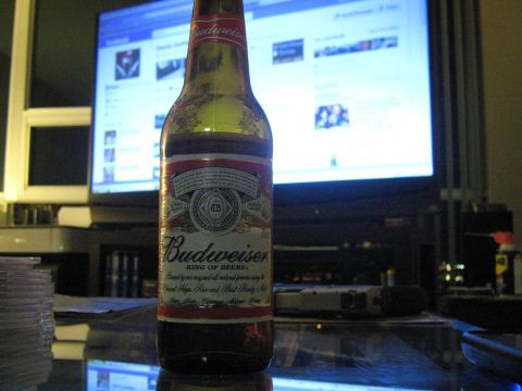 2000 Mercury Grand Marquis - A Budweiser bottle sits on a table in front of a computer monitor displaying a social media feed.