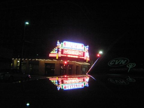 2000 Mercury Grand Marquis - A car hood reflects a neon sign and building at night.