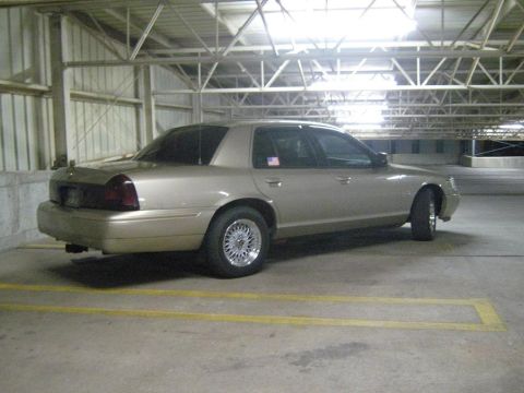 2000 Mercury Grand Marquis - A tan 2000 Mercury Grand Marquis is parked in a dimly lit garage with yellow parking lines.