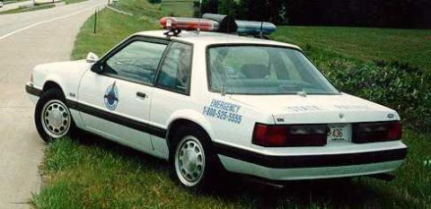 1991 Ford LTD Crown Victoria - A 1991 Ford Crown Victoria police car with emergency lights on top is parked on the side of the road.