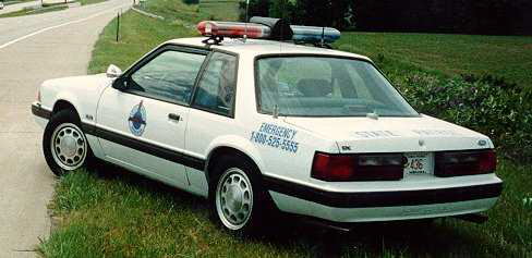 White 1991 Ford Crown Victoria police car parked on grass, side view