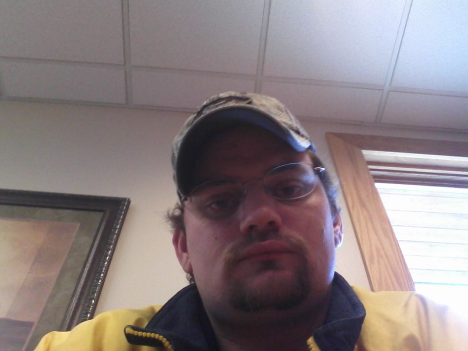 Man in a camouflage cap and glasses taking an indoor selfie