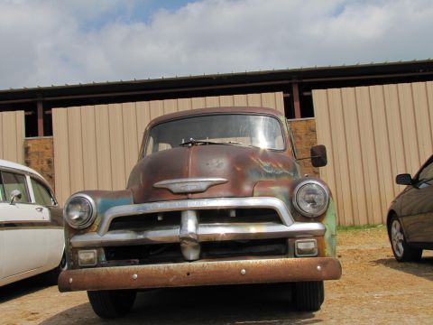 2006 BMW 5 Series - A weathered 1954 Chevrolet truck sits parked outdoors next to other vehicles.