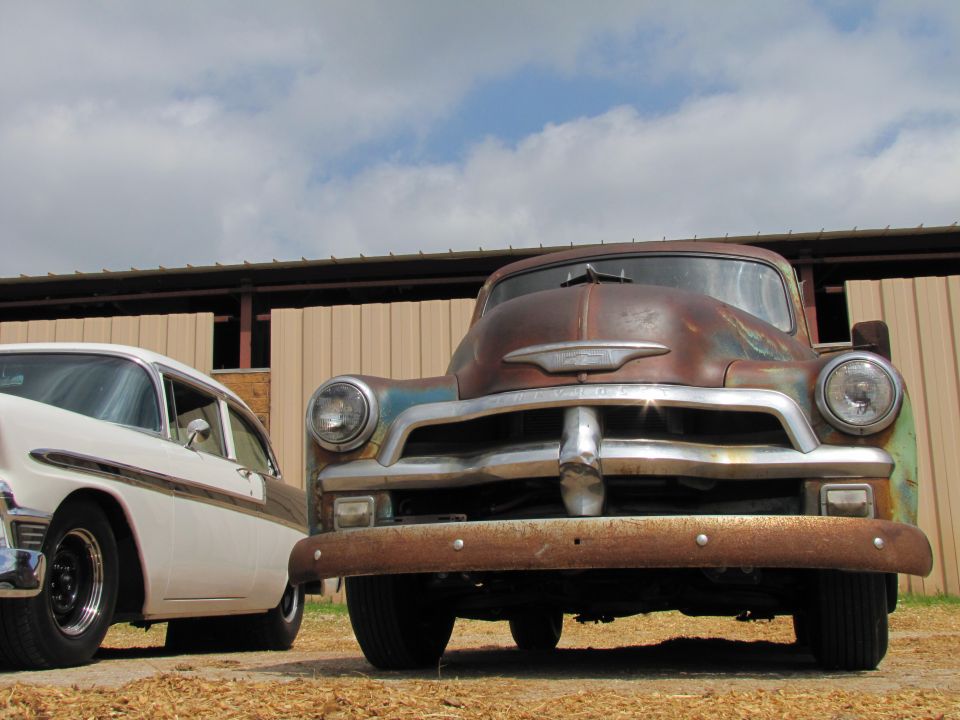 Rusty old truck parked next to a white classic car