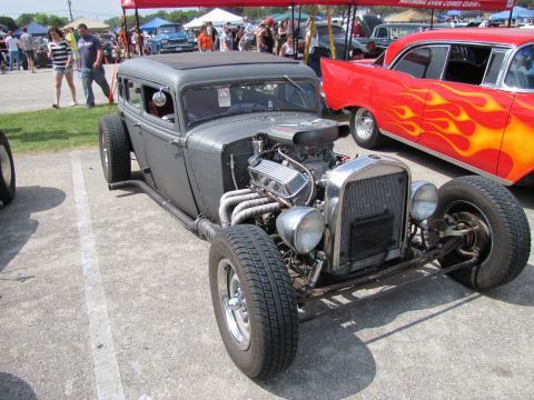2006 BMW 5 Series - A custom hot rod sedan is displayed at an outdoor event with other vehicles.