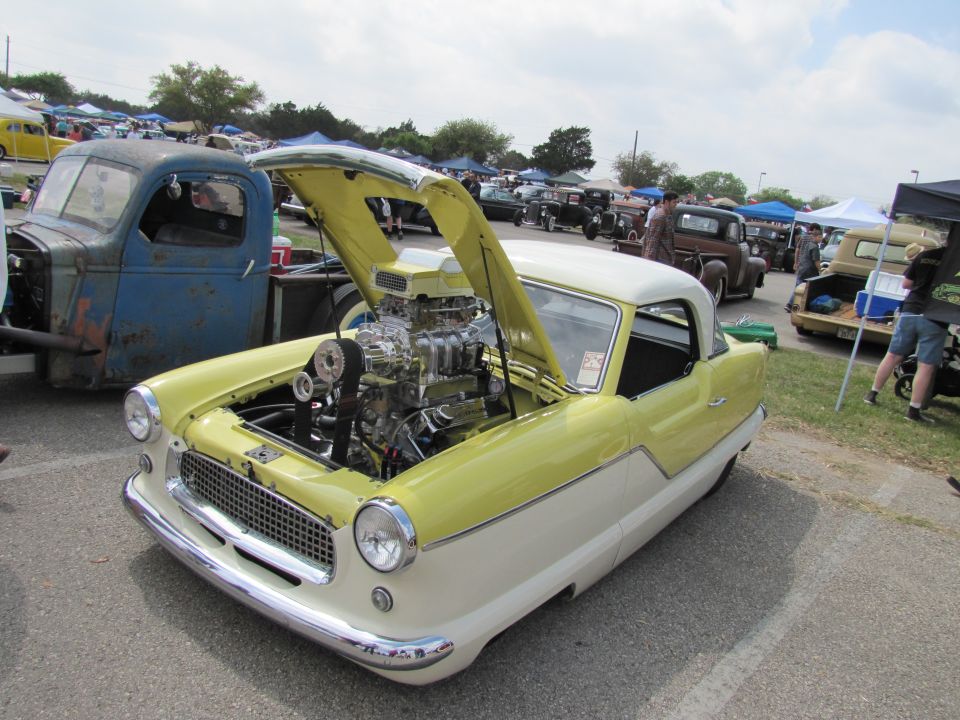 Yellow and white Nash Metropolitan with exposed engine