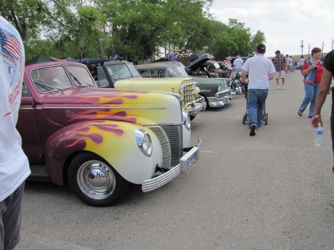 2006 BMW 5 Series - A row of classic cars, including a custom hot rod with flame paint, are displayed at an outdoor event.
