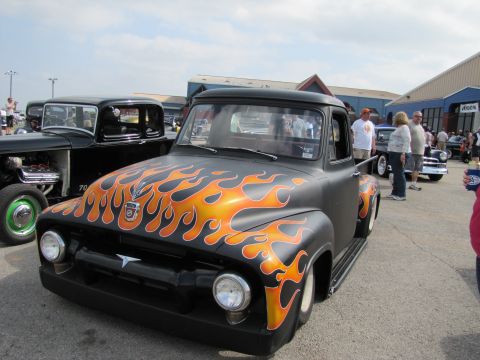 2006 BMW 5 Series - A classic black pickup truck with vibrant flame graphics is displayed at an outdoor event.