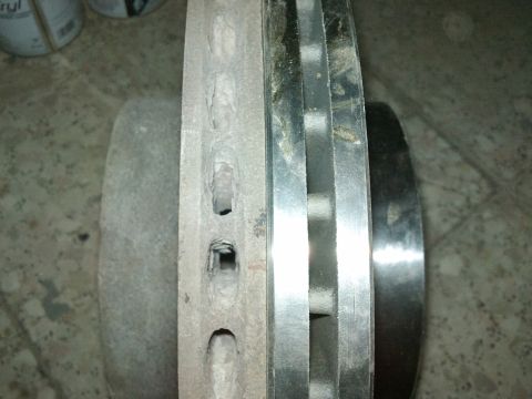 1998 Ford Crown Victoria - A close-up view shows a worn brake rotor with significant grooving and damage to its surface.