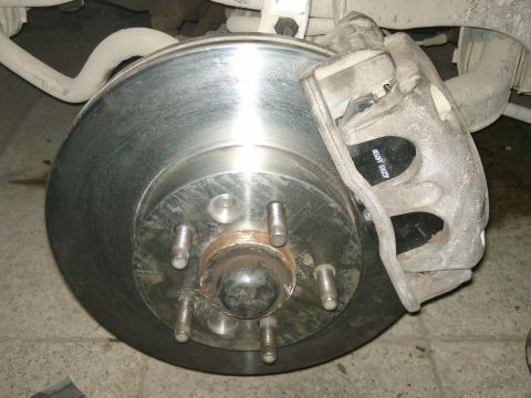 1998 Ford Crown Victoria - Close-up view of a front brake rotor and caliper assembly, showing new brake pads with visible part numbers.