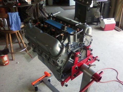 1990 Ford Bronco - Engine assembly on a red stand in a garage setting.