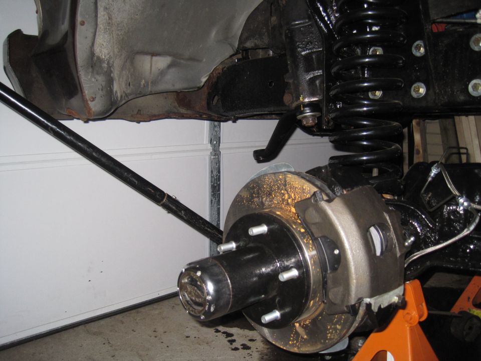 Close-up of a vehicle's front suspension and brake rotor assembly, with a large coil spring visible