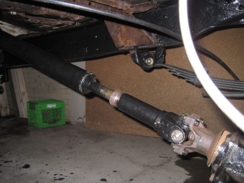 1979 Ford Bronco - Underside view of a vehicle's driveshaft and suspension components, with a green crate visible.