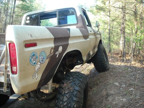 1979 Ford F-150 - Rear view of a lifted 1979 Ford F-150 pickup truck with camouflage paint driving off-road.