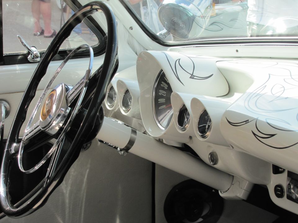 White dashboard with pinstripes, vintage steering wheel, and gauges