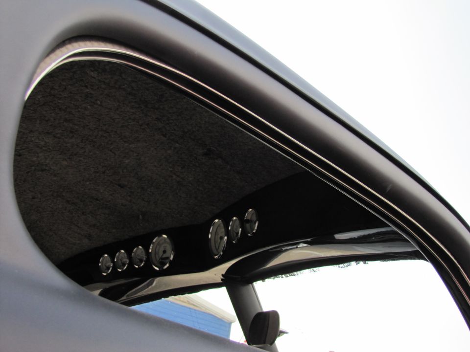 Interior view of a car's custom dashboard showing multiple gauges under the headliner