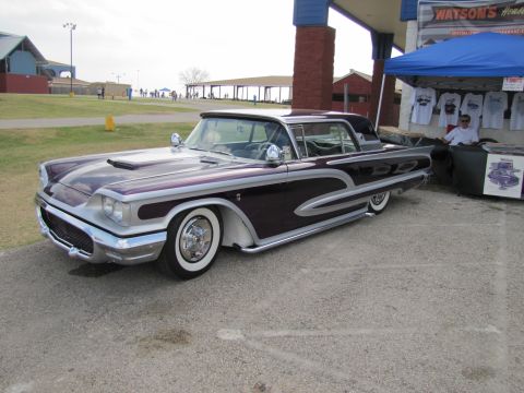 2006 BMW 5 Series - A heavily customized 1958 Ford Fairlane is parked outside a vendor tent.