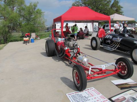 2006 BMW 5 Series - A red dragster is parked next to a black race car under a red tent at an outdoor event.