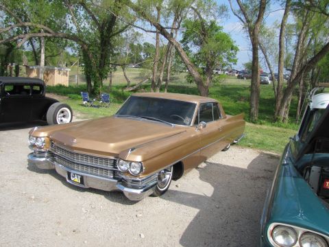 2006 BMW 5 Series - A gold 1965 Cadillac Coupe de Ville is parked outdoors with other vehicles nearby.