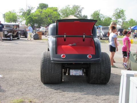 2006 BMW 5 Series - A classic hot rod with oversized rear tires is parked outdoors, with other vehicles and attendees in the background.