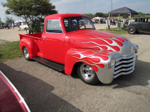 2006 BMW 5 Series - A classic red pickup truck with custom silver flame paintwork is displayed at an outdoor event.