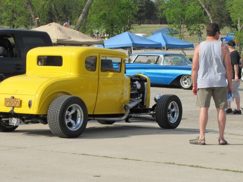 2006 BMW 5 Series - A yellow hot rod coupe is parked at an outdoor event with other vehicles present.