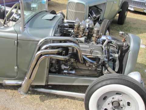 2006 BMW 5 Series - A custom hot rod features a prominent engine with chrome headers and multiple carburetors, with another classic car visible in the backgrou…